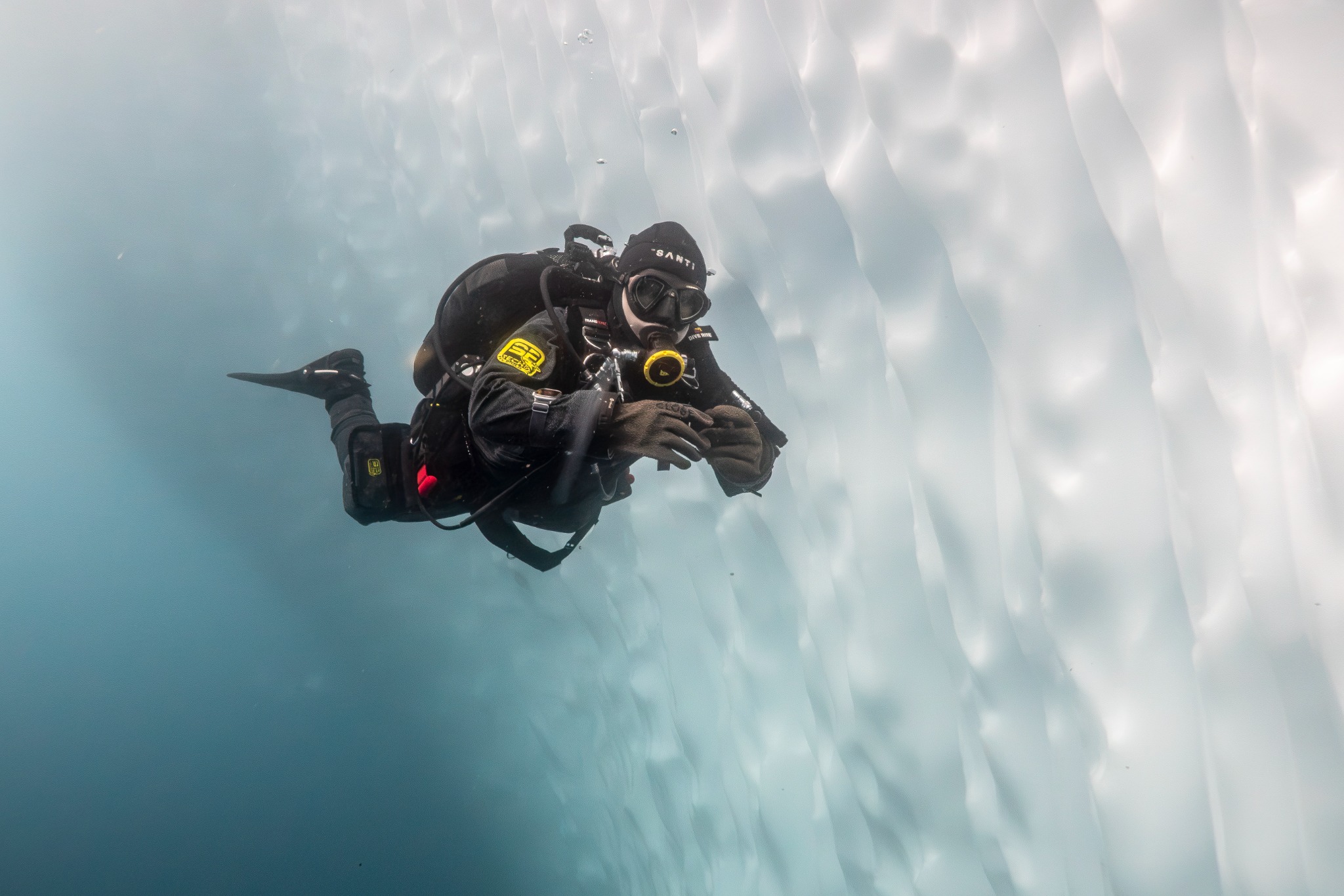 Polar diver swimming beside an Antarctic ice wall
